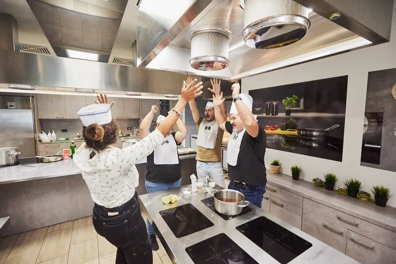 chef amatoriali che festeggiano intorno al piano di lavoro in cucina