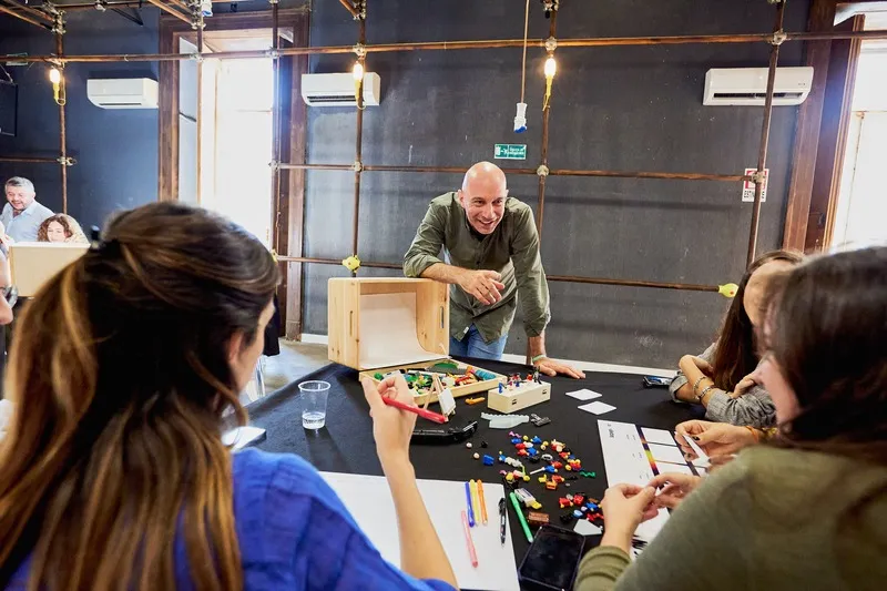 3 people speaking at a desk with LEGO on it