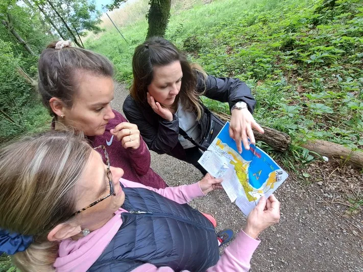 Tre ragazze che guardano una mappa di un percorso orienteering