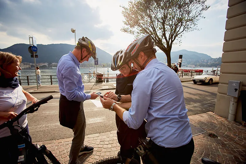 Persone che guardano mappa su smartphone con casco bicicletta a Como