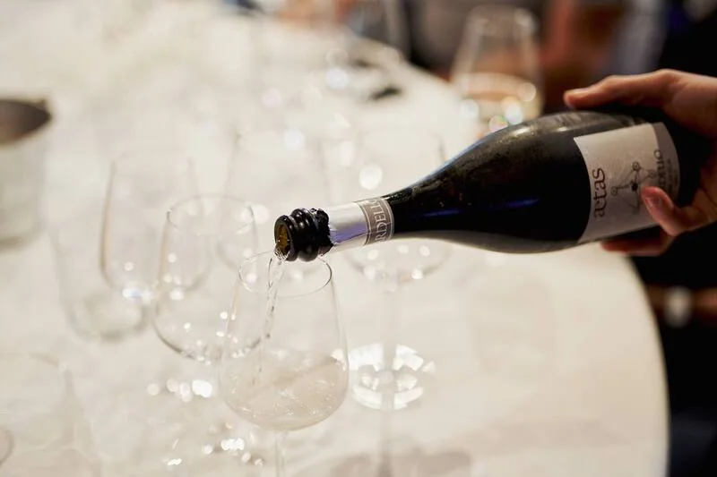 Tavolo con bicchieri e mano che versa del vino bianco