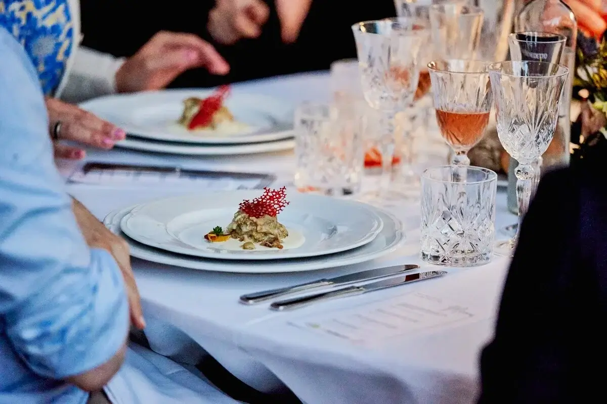 Tavola apparecchiata dove viene servita una cena di gala