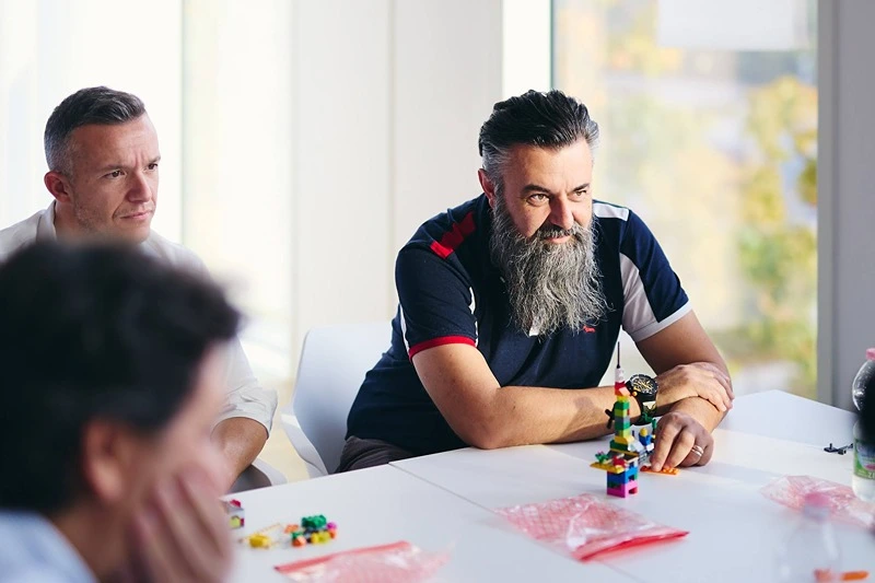 Tre persone ad un tavolo che fanno team building con i mattoncini LEGO