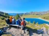 Ragazzi seduti su una panchina di legno che ammirano un lago di montagna
