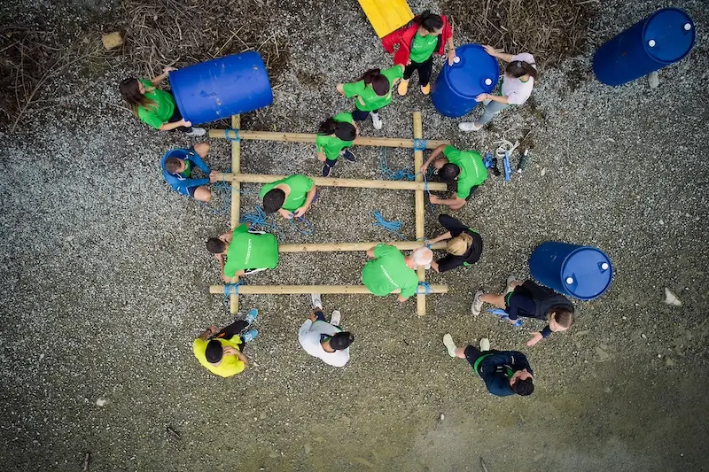 team di lavoro che costruisce una zattera in legno sulla spiaggia