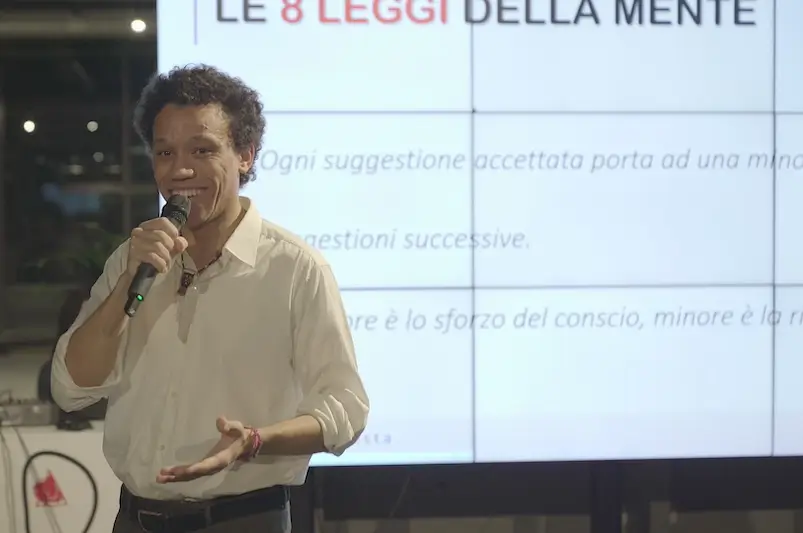mentalista che parla con uno schermo sullo sfondo