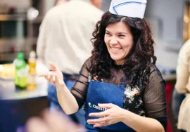 Ragazza del team che sorride in cucina con cappello da cuoco