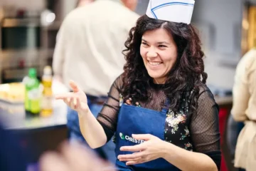 Ragazza del team che sorride in cucina con cappello da cuoco