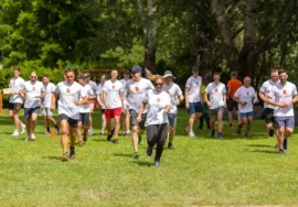 Dipendenti aziendali che partecipano a una corsa di team building in un parco verde in Lombardia, indossando magliette personalizzate.