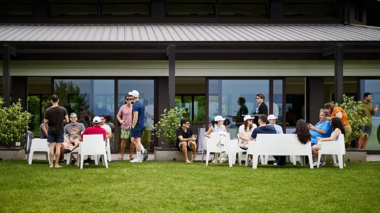 Partecipanti all’evento di team building HPLY seduti in gruppo nel giardino di Villa Repui a Besozzo, mentre conversano in un momento di networking informale.
