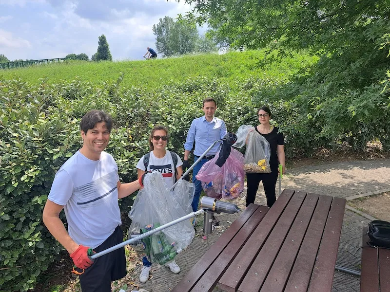 Gruppo aziendale mostra con orgoglio i sacchi pieni dopo l’attività di volontariato ambientale a Milano, zona Parco Nord.