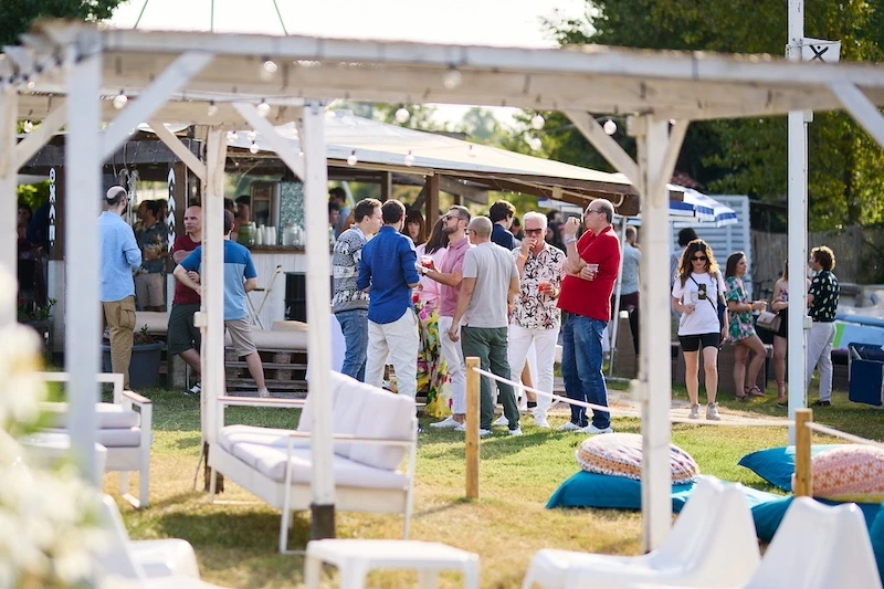 Gruppo di partecipanti che socializzano durante un aperitivo outdoor in un summer party aziendale immerso nel verde vicino a Milano