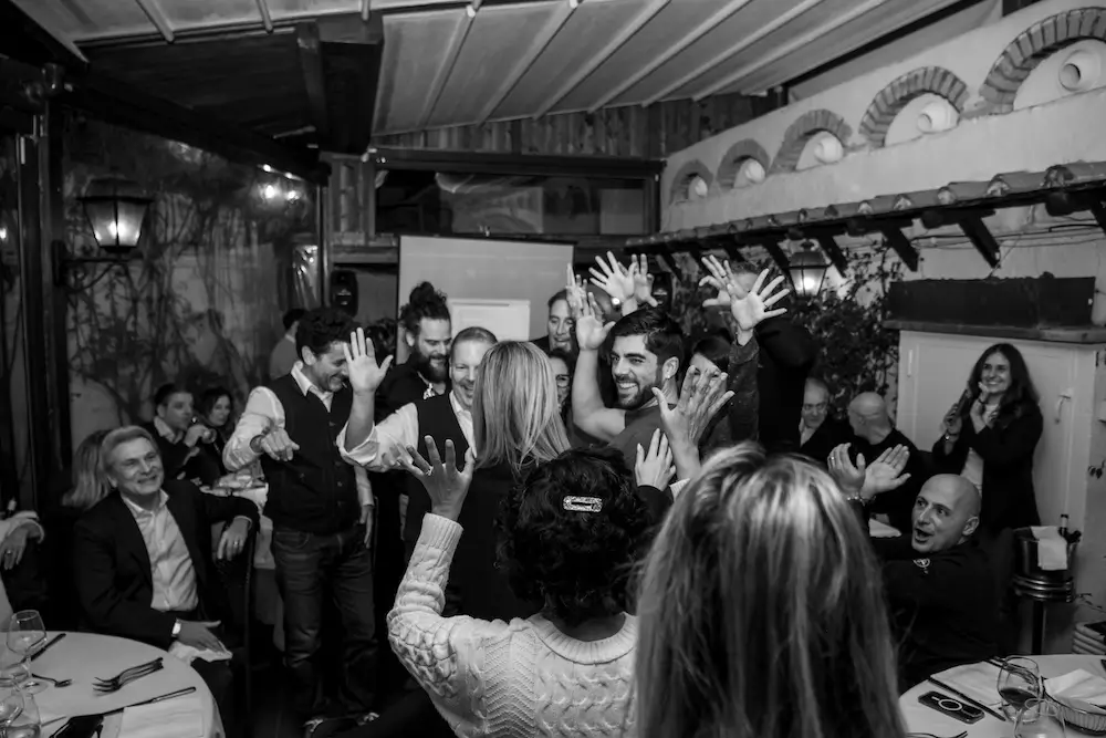 Foto in bianco e nero di un gruppo di colleghi di lavoro che ballano facendo team building e sostenibilità sociale