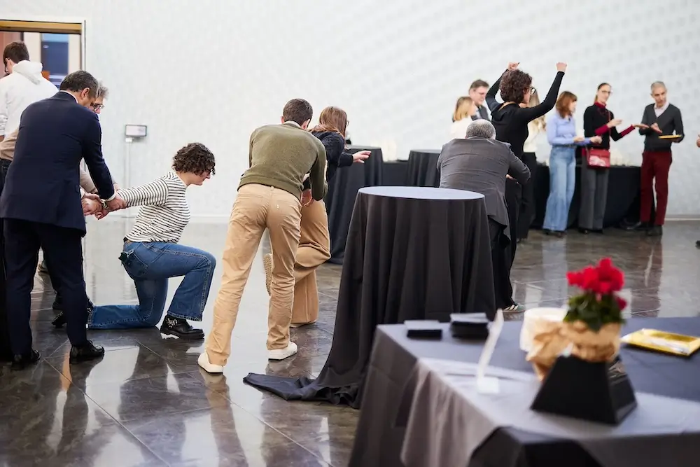 team building solidale con colleghi di lavoro che stanno in posa mentre il regista gira per la stanza con la videocamera
