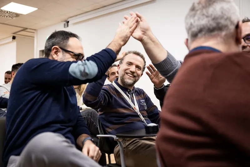 Partecipanti sorridono e partecipano con entusiasmo a un’attività di team building TeamQuest